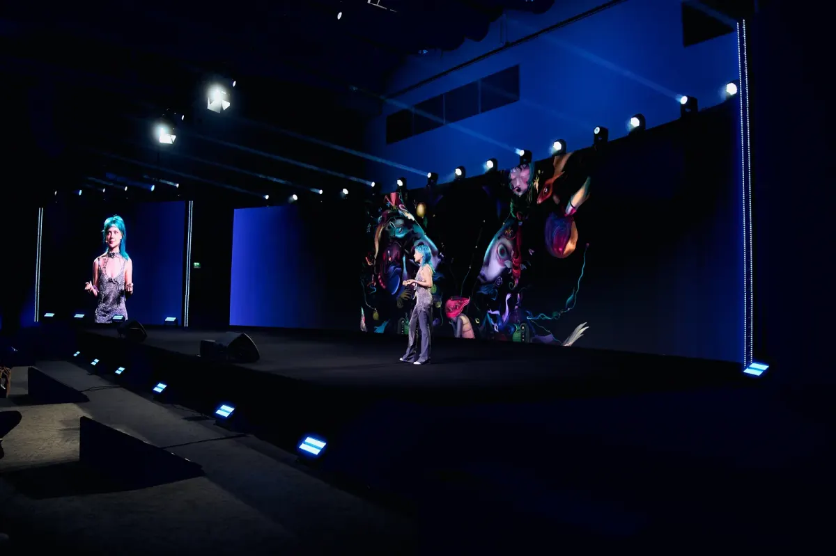 Presenter on a lit event stage with a large backdrop at a conference or MICE production in Dubai