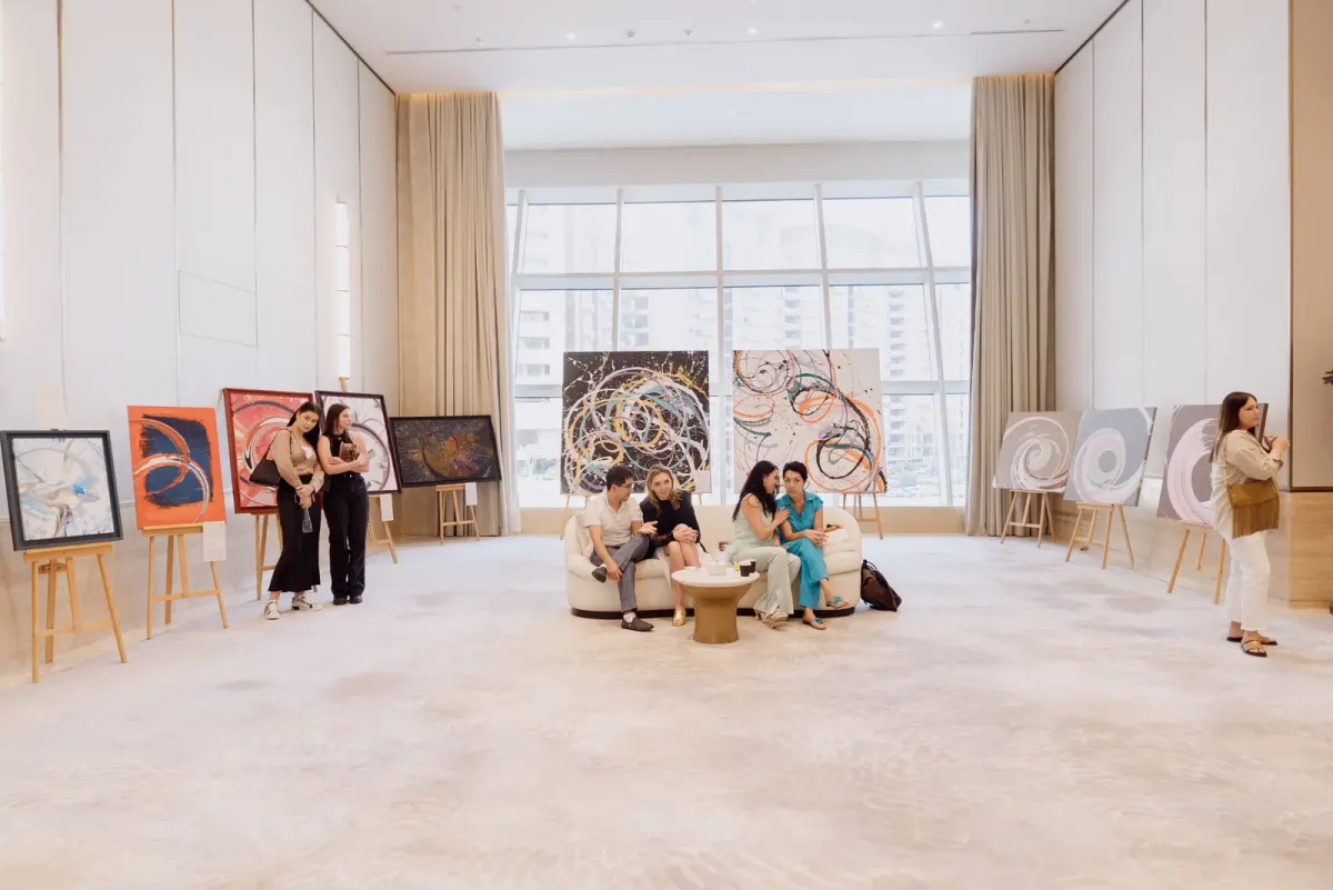 Indoor event space with guests seated beside paintings on easels in Dubai Indoor event space with guests seated beside paintings on easels in Dubai
